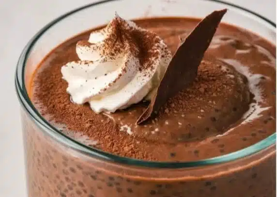 High protein chocolate chia pudding in a bowl topped with berries and mint.