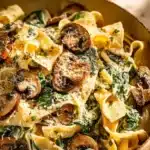 Creamy Parmesan Spinach Mushroom Pasta garnished with fresh herbs in a bowl