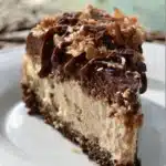 Slice of German Chocolate Cheesecake topped with coconut and pecan frosting