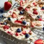 Frozen yogurt bark topped with fresh berries and nuts on a white plate