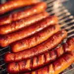 Delicious marinated grilled hot dogs on a BBQ grill.