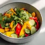 A colorful bowl of Thai Mango Salad with fresh mango, herbs, and vegetables.