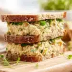 Chickpea salad sandwich with fresh vegetables and herbs on whole grain bread.