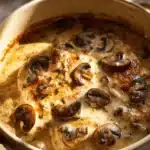 Creamy mushroom chicken dish garnished with fresh herbs