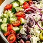 A vibrant Greek Salad with cucumbers, tomatoes, red onions, olives, and feta cheese.