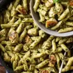 Creamy chicken pesto pasta dish with fresh ingredients and vibrant colors.