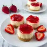Mini strawberry cheesecakes topped with fresh strawberries on a serving plate