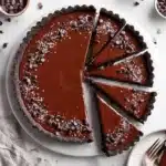 No-bake vegan chocolate tart topped with fresh fruits and cacao nibs
