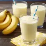 Pineapple, banana, and coconut smoothie served in a glass with tropical fruits