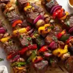 Grilled steak kabobs served with colorful bell peppers and onions on skewers.